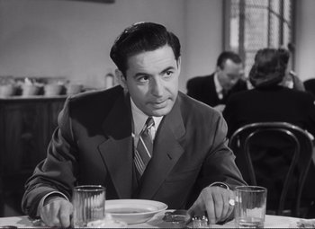 Movie still from “The Snake Pit” (1948), directed by Anatole Litvak – A black and white photo of a man sitting at a dinner table; Medium shot, Over the shoulder angle