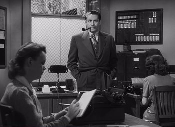 Movie still from “The Snake Pit” (1948), directed by Anatole Litvak – A man in a suit and tie standing in front of a typewriter; Medium shot, Low angle