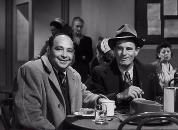Movie still from “The Snake Pit” (1948), directed by Anatole Litvak – A couple of men sitting at a table with a drink; Medium shot, Low angle