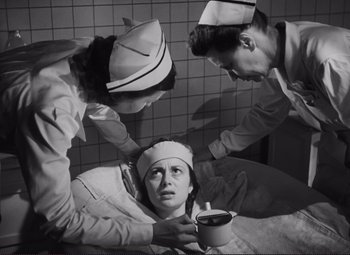 Movie still from “The Snake Pit” (1948), directed by Anatole Litvak – A woman is being examined by two nurses in a room with tiled walls and a tiled floor; Medium shot, Low angle