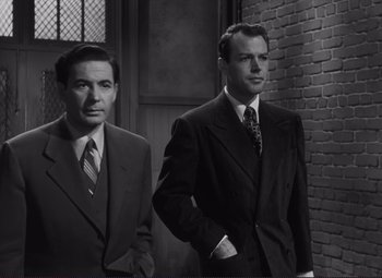 Movie still from “The Snake Pit” (1948), directed by Anatole Litvak – Two men standing next to each other wearing suits; Medium shot, Low angle