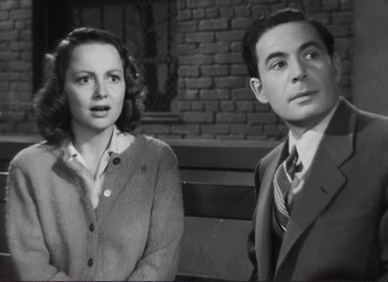 Movie still from “The Snake Pit” (1948), directed by Anatole Litvak – A man and a woman standing next to each other in front of a brick wall; Medium shot, High angle