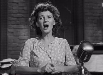 Movie still from “The Snake Pit” (1948), directed by Anatole Litvak – An old photo of a woman singing into a microphone; Medium shot, Low angle