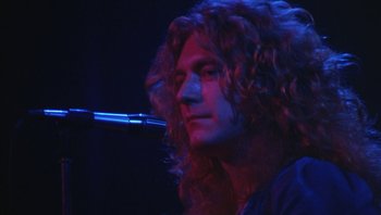 Movie still from “The Song Remains the Same” (1976), directed by Peter Clifton – A person with long hair; Close Up shot, Low angle