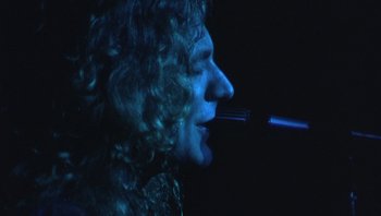 Movie still from “The Song Remains the Same” (1976), directed by Peter Clifton – A man with curly hair is smoking a pipe; Extreme Close Up shot, Low angle
