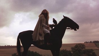 Movie still from “The Song Remains the Same” (1976), directed by Peter Clifton – A woman sitting on top of a black horse; Wide shot, Low angle
