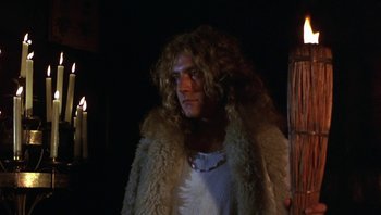 Movie still from “The Song Remains the Same” (1976), directed by Peter Clifton – A man in a white shirt and a white fur coat; Medium shot, Low angle