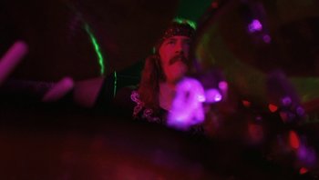 Movie still from “The Song Remains the Same” (1976), directed by Peter Clifton – A man with a long hair and a beard wearing a wig; Close Up shot, Low angle