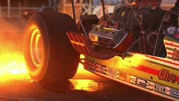 Movie still from “The Song Remains the Same” (1976), directed by Peter Clifton – The front wheel of a race car; Wide shot, Low angle