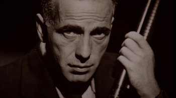 Movie still from “The Sopranos” (1999), created by David Chase – An older man in a suit and tie holding a microphone; Extreme Close Up shot, Low angle