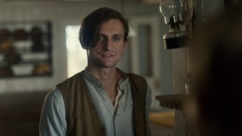 Movie still from “Anne with an E” (2017), created by Moira Walley-Beckett – A man with long brown hair standing in front of a fire place; Close Up shot, Low angle