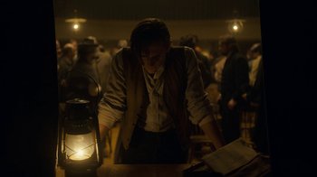Movie still from “Anne with an E” (2017), created by Moira Walley-Beckett – A man standing next to an open book in front of a lantern; Medium shot, Low angle