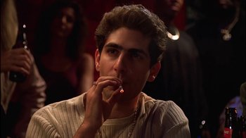 A young man smoking a cigarette in front of a crowd