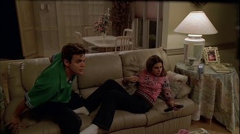 Movie still from “The Sopranos” (1999), created by David Chase – A man and a woman sitting on a couch watching television; Medium shot, High angle