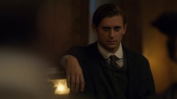 Movie still from “Anne with an E” (2017), created by Moira Walley-Beckett – A man wearing a suit and tie leaning on a wall; Medium shot, Over the shoulder angle
