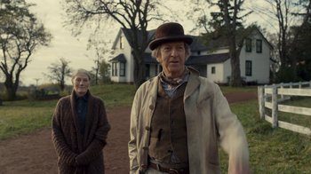 Movie still from “Anne with an E” (2017), created by Moira Walley-Beckett – An older man and woman standing in front of a house; Medium shot, Over the shoulder angle