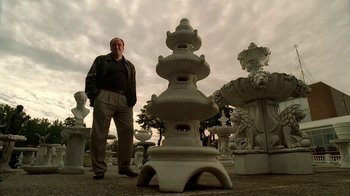 Movie still from “The Sopranos” (1999), created by David Chase – A man standing in front of a group of statues; Medium shot, Low angle