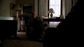 Movie still from “The Sopranos” (1999), created by David Chase – An older man sitting in a chair in a living room; Wide shot, High angle