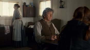 Movie still from “Anne with an E” (2017), created by Moira Walley-Beckett – An older man sitting at a table in front of a window; Medium shot, Over the shoulder angle