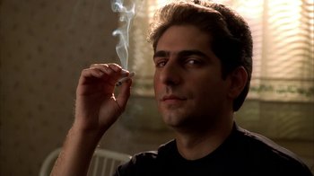 Movie still from “The Sopranos” (1999), created by David Chase – A young man smoking a cigarette in a dark room; Close Up shot, Low angle