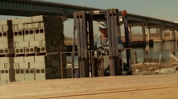 Movie still from “The Sopranos” (1999), created by David Chase – A man standing in front of a fork lift; Wide shot, Low angle