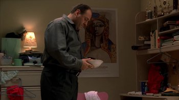 Movie still from “The Sopranos” (1999), created by David Chase – A man standing in a room holding a plate; Medium shot, Low angle
