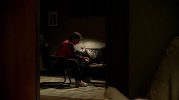 Movie still from “The Sopranos” (1999), created by David Chase – A man sitting in a chair with a laptop; Wide shot, Over the shoulder angle