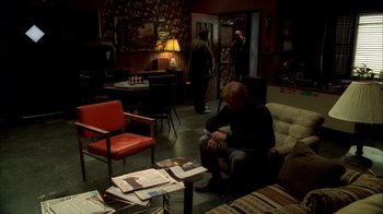 Movie still from “The Sopranos” (1999), created by David Chase – A man sitting on a chair in a living room; Wide shot, High angle