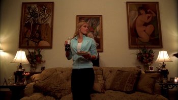 Movie still from “The Sopranos” (1999), created by David Chase – A woman standing in front of a couch holding a tray of food; Medium shot, Low angle