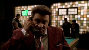Movie still from “The Sopranos” (1999), created by David Chase – A man talking on a phone while wearing a suit and tie; Medium shot, Low angle