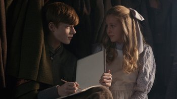 Movie still from “Anne with an E” (2017), created by Moira Walley-Beckett – A boy and a girl are looking at each other while holding a laptop; Medium shot, High angle