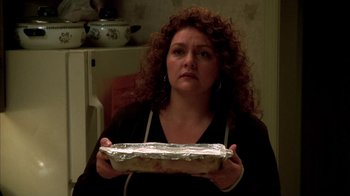 Movie still from “The Sopranos” (1999), created by David Chase – A woman holding a pan of food in front of her face; Close Up shot, High angle