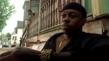 Movie still from “The Sopranos” (1999), created by David Chase – A man sitting on a bench in front of a building; Close Up shot, Low angle