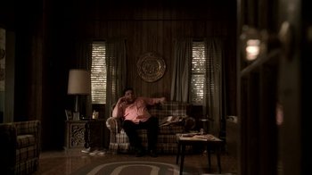 Movie still from “The Sopranos” (1999), created by David Chase – A man sitting on top of a couch in a living room; Wide shot, High angle