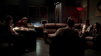 Movie still from “The Sopranos” (1999), created by David Chase – Two men are sitting in a dark room; Wide shot, High angle