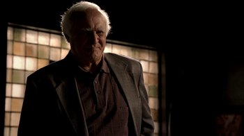 Movie still from “The Sopranos” (1999), created by David Chase – An older man wearing a suit and tie in front of a window; Close Up shot, Over the shoulder angle