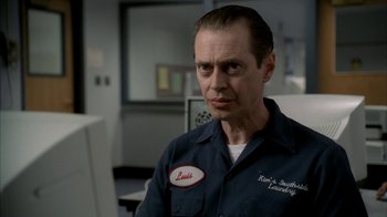 Movie still from “The Sopranos” (1999), created by David Chase – A man in a blue work shirt with a red patch on his chest; Close Up shot, Over the shoulder angle