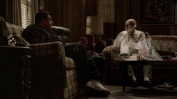 Movie still from “The Sopranos” (1999), created by David Chase – Two men are sitting in a living room talking; Wide shot, High angle