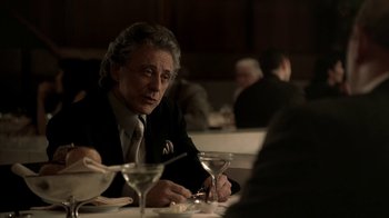 Movie still from “The Sopranos” (1999), created by David Chase – An older man sitting at a table in a restaurant; Medium shot, Over the shoulder angle