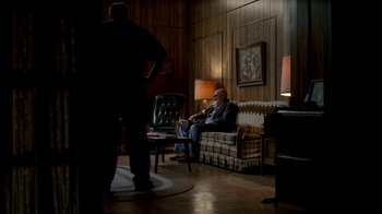 Movie still from “The Sopranos” (1999), created by David Chase – A man sitting on top of a couch in a living room; Wide shot, High angle