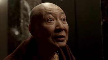 Movie still from “The Sopranos” (1999), created by David Chase – An old man with a bald head wearing a brown robe; Close Up shot, Low angle