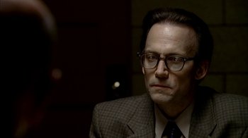 Movie still from “The Sopranos” (1999), created by David Chase – A man in a suit and glasses looking to his left; Close Up shot, Over the shoulder angle