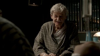 Movie still from “The Sopranos” (1999), created by David Chase – An older man sitting in a chair in front of a window; Close Up shot, Over the shoulder angle