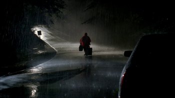 Movie still from “The Sopranos” (1999), created by David Chase – A man in a red raincoat walking down a street; Extreme Wide shot, High angle