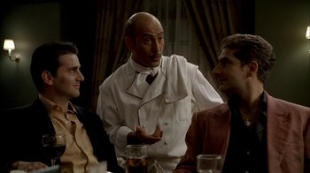 Movie still from “The Sopranos” (1999), created by David Chase – Three men sitting at a dinner table talking to each other; Medium shot, Over the shoulder angle