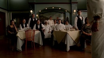 Movie still from “The Sopranos” (1999), created by David Chase – A group of people sitting at a table with plates; Wide shot, High angle