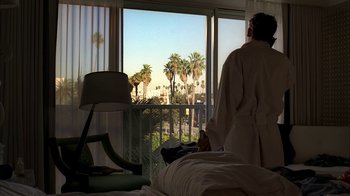Movie still from “The Sopranos” (1999), created by David Chase – A man in a robe looking out a window at the beach; Medium shot, Over the shoulder angle