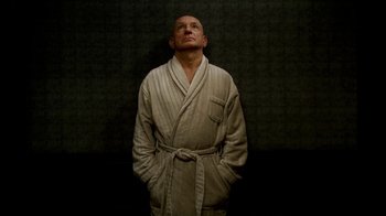Movie still from “The Sopranos” (1999), created by David Chase – A man in a robe standing in front of a black wall; Medium shot, Low angle