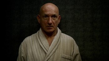 Movie still from “The Sopranos” (1999), created by David Chase – A bald man in a white robe stares into the camera; Close Up shot, High angle