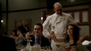 Movie still from “The Sopranos” (1999), created by David Chase – A man pouring wine into a glass at a dinner table; Medium shot, Over the shoulder angle